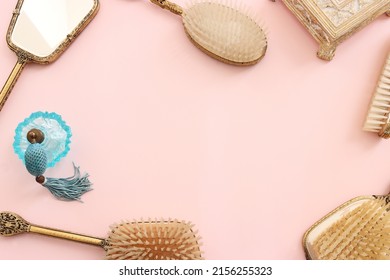 Image Of Vintage Hair Comb, Perfume Bottle And Hand Mirror Over Pastel Pink Background