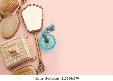 Image Of Vintage Hair Comb, Perfume Bottle And Hand Mirror Over Pastel Pink Background