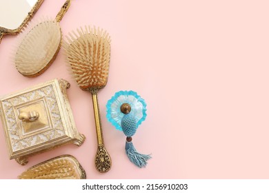 Image Of Vintage Hair Comb, Perfume Bottle And Hand Mirror Over Pastel Pink Background