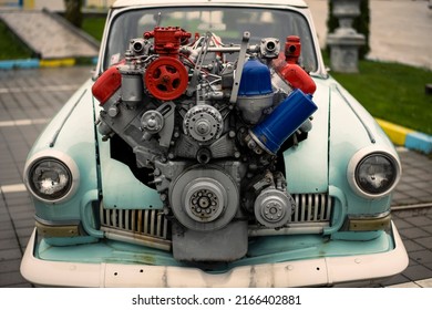 Image of a vintage tuned car, with a large engine sticking out of its hood.