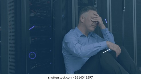 Image of violet shapes and eye over stressed caucasian man sitting at servers. cloud computing, data uploading, computers and technology concept digitally generated image.