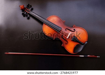 Image of a violin with a bow, a string instrument typically used in classical and folk music on black background. 