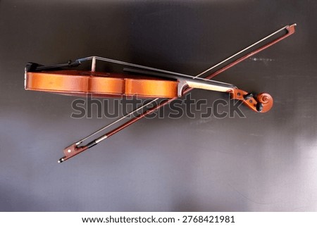 Image of a violin with a bow, a string instrument typically used in classical and folk music on black background. 