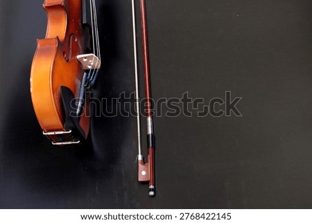 Image of a violin with a bow, a string instrument typically used in classical and folk music on black background. 