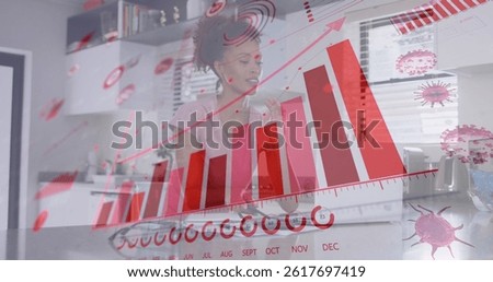 Image of virus cells and graphs over biracial woman working from home. global covid 19 pandemic, health and home office concept digitally generated image.