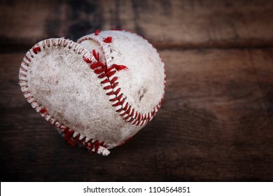 Image of a well loved baseball splitting at the seams forming a heart shape