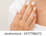 An image with well-groomed nails and jewelry concept. Female model shows a gold elegant ring on her finger. Jewelry photography for e-commerce, social media and all platforms.