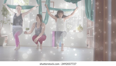 Image of white light spots over diverse female instructor and teenage girls doing aerial yoga. Wellbeing, energy, fitness and healthy lifestyle, digitally generated image. - Powered by Shutterstock