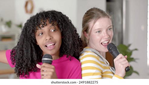 Image of white lights over happy diverse teenage girls with microphones singing karaoke at home. Friendship, youth, free time, music, fun, weekend and lifestyle, digitally generated image. - Powered by Shutterstock