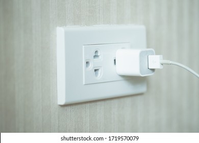 Image Of White Plug In Electric Socket On Wall.