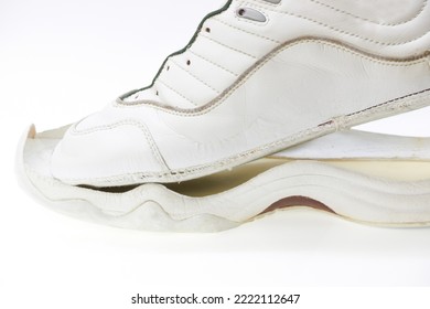 Image of white sneakers with peeling soles.