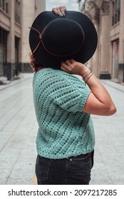 Image Of A Woman Hiding Her Face With A Black Hat In The Middle Of A Lonely Street