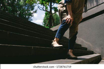 Image Of A Woman Holds Her Leg While Walking Down On Stairs. Pain And Suffering From Patellar Tendonitis, Medical Symptom Concept.