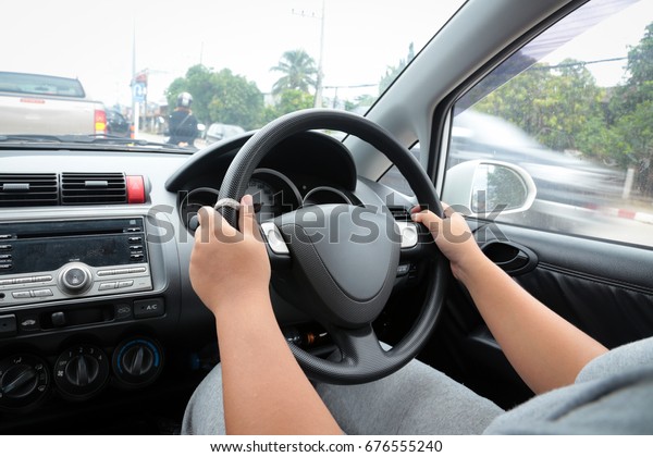 The image of a woman\'s hand using both hands\
driving a car carefully for\
safety.
