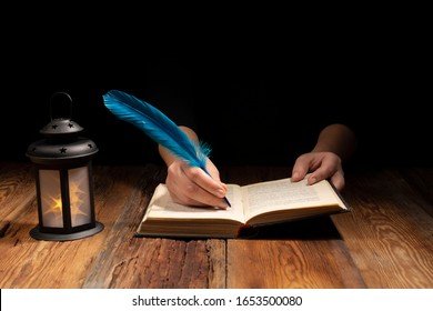 An Image Of Women's Hands Making Notes With A Stationery Pen In An Open Book By The Light Of A Dim Lamp On A Wooden Vintage Table