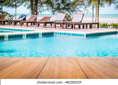 Image Of Wood Table In Front Of A Swimming Pool Background. Brown Wooden Desk Empty Counter In Front Of The Poolside On Beautiful Beach Resort And Outdoor Spa Vacation Day.