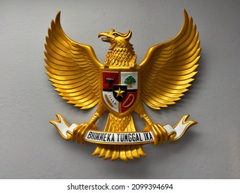 image of a wooden statue of Garuda Pancasila, the Republic of Indonesia's national symbol. The meaning of Bhinneka Tunggal Ika is "Unity in Diversity". - Shutterstock ID 2099394694