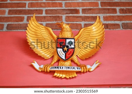 image of a wooden statue of Garuda Pancasila, the Republic of Indonesia's national symbol. The meaning of Bhinneka Tunggal Ika is 