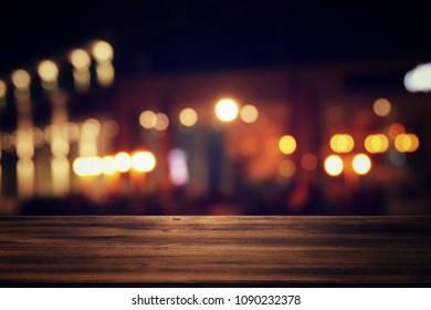 Image of wooden table in front of abstract blurred restaurant lights background - Shutterstock ID 1090232378