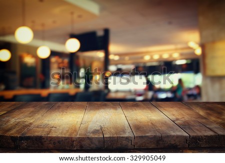 image of wooden table in front of abstract blurred background of restaurant lights
