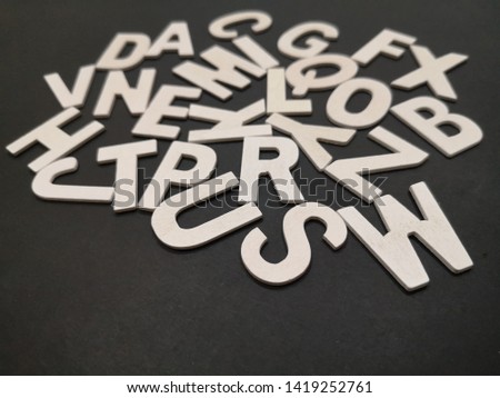 Image of wooden white alphabet letters with black color background.