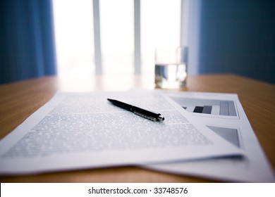 Image of workplace with focus on papers and pen on the table