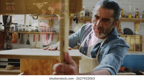 Image of world map and data processing over caucasian male carpenter working in workshop.global communication, work and digital interface concept digitally generated image.