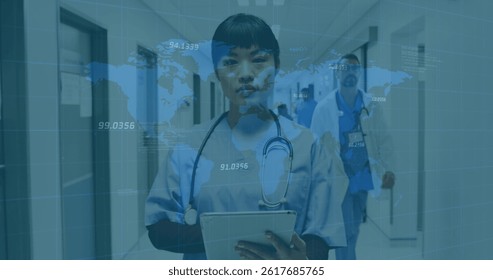 Image of world map and financial data over asian female doctor making notes. health, medical profession, economy, finance and technology concept digitally generated image.
