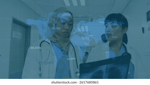 Image of world map and financial data over diverse female doctors with x ray photo. health, medical profession, economy, finance and technology concept digitally generated image.