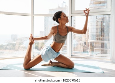 Image of a young amazing concentrated fitness african woman making yoga stretching exercises on a rug indoors - Shutterstock ID 1825390613