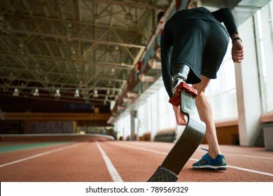 Image of young amputee athlete on start position on running track in modern indoor stadium, focus on artificial foot, copy space - Powered by Shutterstock