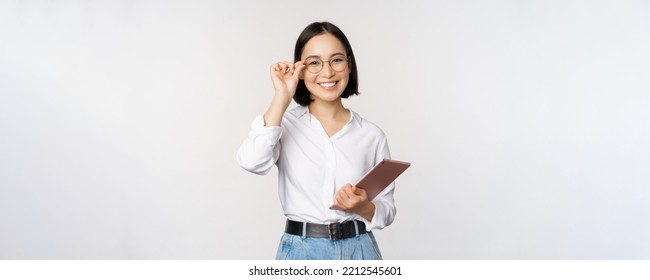 Image of young asian business woman, female entrepreneur in glasses, holding tablet and looking professional in glasses, white background - Powered by Shutterstock