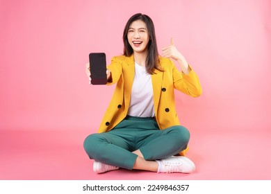 Image of young Asian businesswoman sitting and holding smartphone on background - Powered by Shutterstock