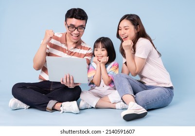 Image Of Young Asian Family Using Laptop On Blue Background