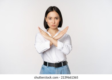 Image of young asian, korean girl student showing stop, cross prohibition sign, forbid smth, refusing, standing over white background