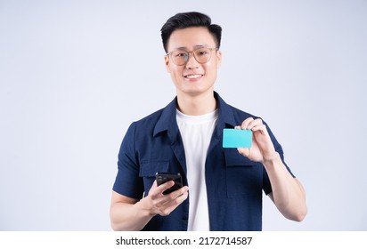 Image Of Young Asian Man Holding Bank Card On White Background