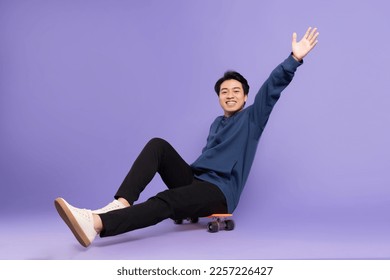 Image of young Asian man playing skateboard on purple background - Powered by Shutterstock