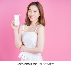 Image Of Young Asian Woman Holding Milk Carton On Pink Background