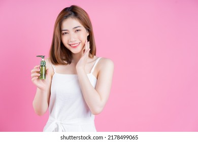 Image Of Young Asian Woman Holding Spray Bottle On Pink Background