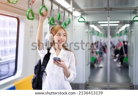 Image of young Asian woman using smartphone on the metro