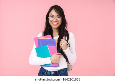 Image Of Young Brunette Asian Student Girl Wearing Eyeglasses Holding Paper Folders Isolated Over Pink Background