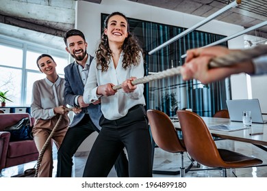 Image of young business team taking competitive advantage playing pulling rope with they work partners. Office setting. Team building concept
