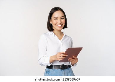 Image of young ceo manager, korean working woman holding tablet and smiling, standing over white background - Powered by Shutterstock