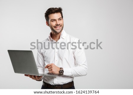 Image of young cheerful businessman in wristwatch holding and using laptop isolated over white background