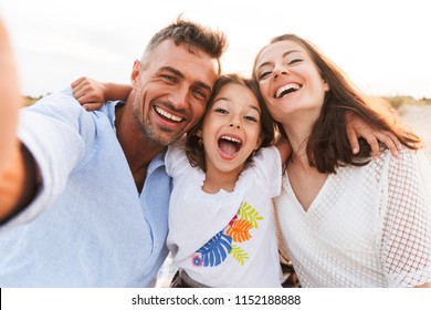 Image of young cheerful excited family outdoors at the beach take a selfie by camera. - Powered by Shutterstock