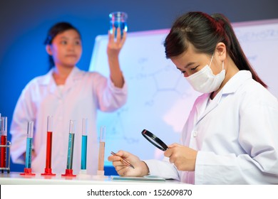 Image of a young chemist analyzing the results with a magnifier on the foreground