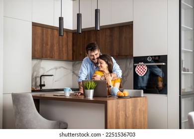 Image of young couple in the kitchen, using laptop computer. - Powered by Shutterstock