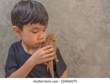 image of young cute Asian boy hold Bearded Dragon on his shoulder.