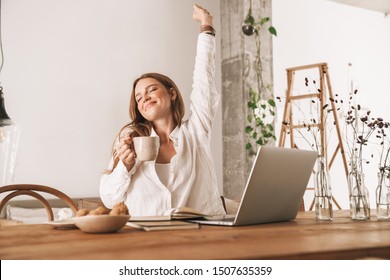 Image of young cute redhead business woman sit indoors in office stretching drinking coffee. - Powered by Shutterstock