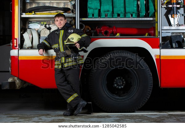 Image of young\
fireman man near fire\
truck